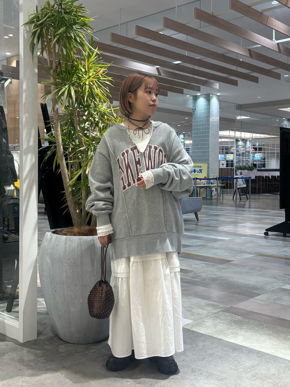 ブラウン系のショルダーバッグ、ホワイト系のワンピース、グレー系のスウェットを着用したレディースの冬コーディネートの2枚目の写真