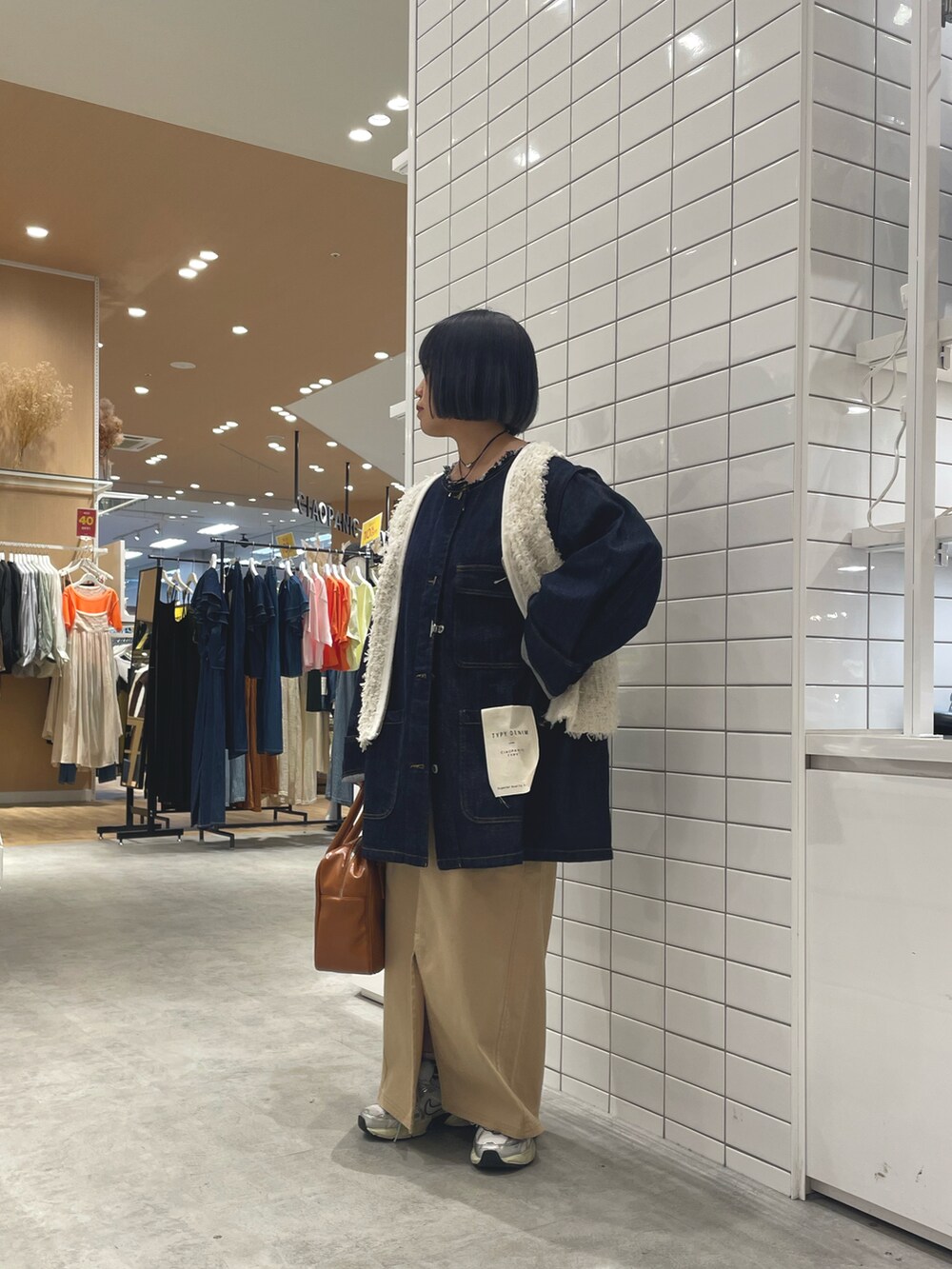 ホワイト系のスニーカー、ホワイト系のベスト、ブルー系のデニムジャケットを着用したレディースの秋コーディネートの3枚目の写真