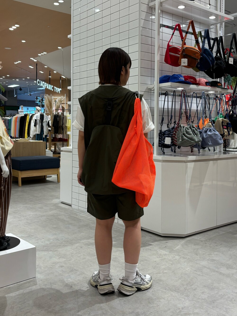 ホワイト系のTシャツ/カットソー、オレンジ系のトートバッグ、グリーン系のベストを着用したレディースの春コーディネートの2枚目の写真