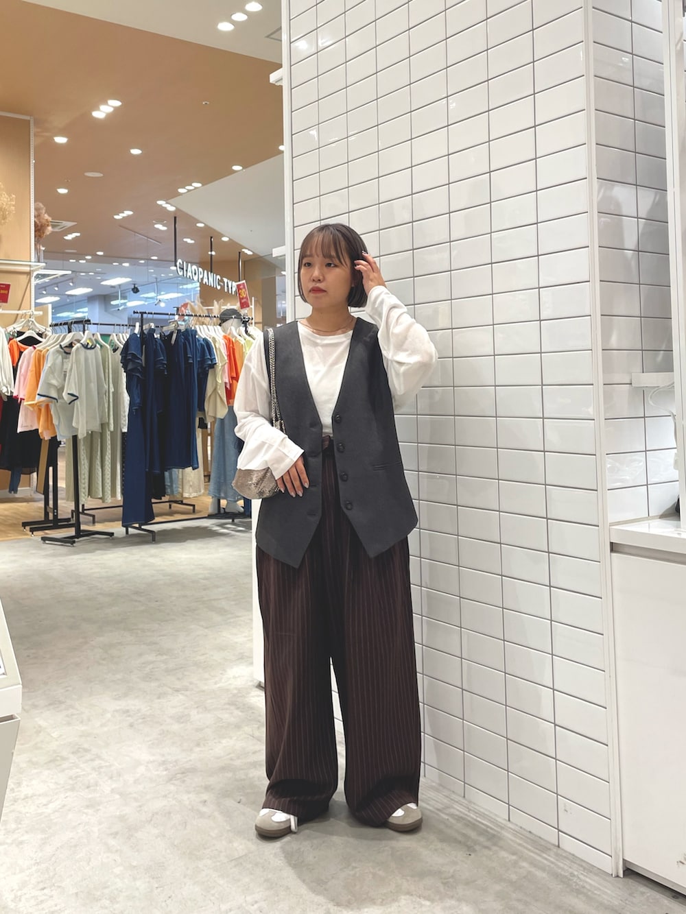 ホワイト系のTシャツ/カットソー、グレー系のベスト、ブラウン系のスラックスを着用したレディースの秋コーディネートの2枚目の写真