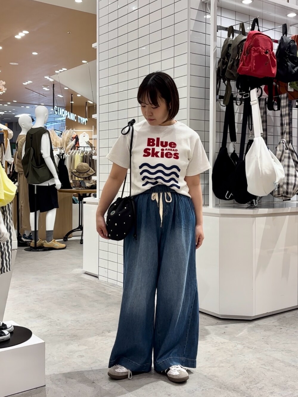 ブルー系のデニムパンツ、ホワイト系のTシャツ/カットソー、ブラック系のハンドバッグを着用したレディースの夏コーディネートの2枚目の写真