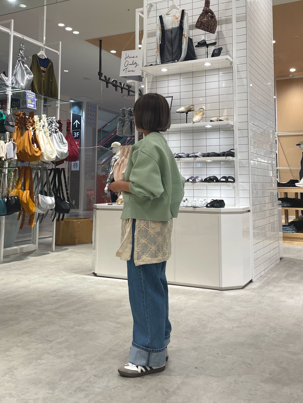 グリーン系のニット/セーター、ホワイト系のTシャツ/カットソー、ホワイト系のスカートを着用したレディースの秋コーディネートの2枚目の写真