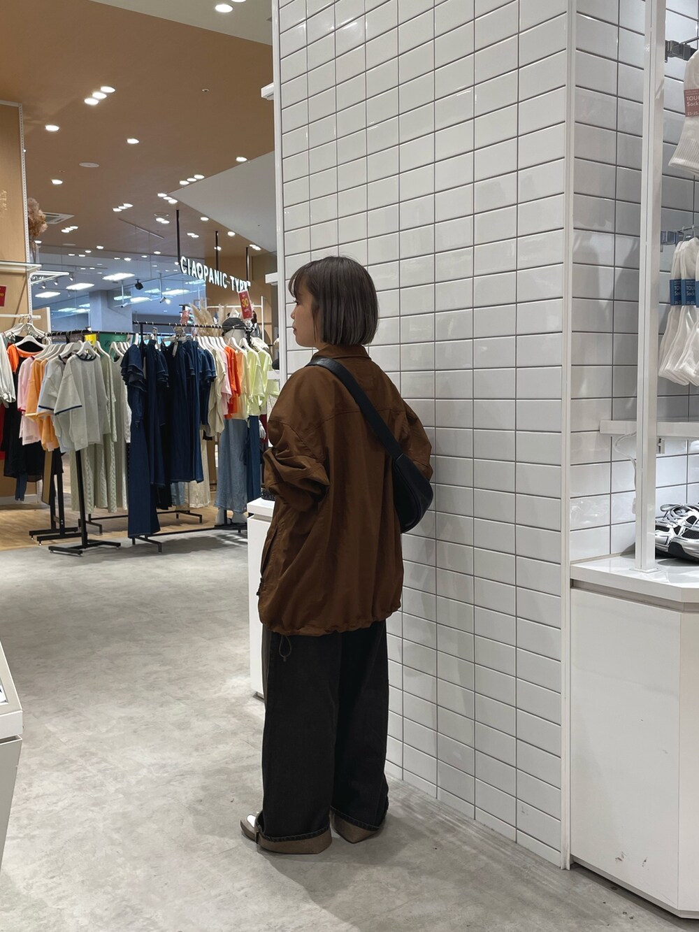 ブラウン系のナイロンジャケット、ブラック系のショルダーバッグ、ブラウン系のデニムパンツを着用したレディースの秋コーディネートの2枚目の写真