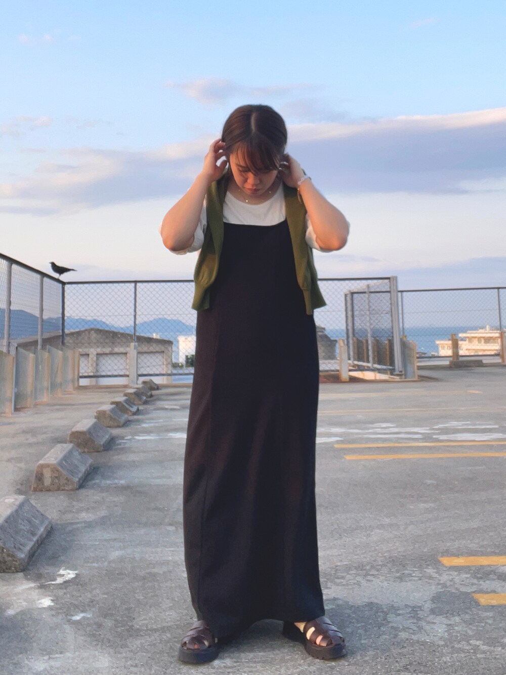 グリーン系のカーディガン/ボレロ、ホワイト系のTシャツ/カットソー、ブラック系のワンピースを着用したレディースの春コーディネートの2枚目の写真