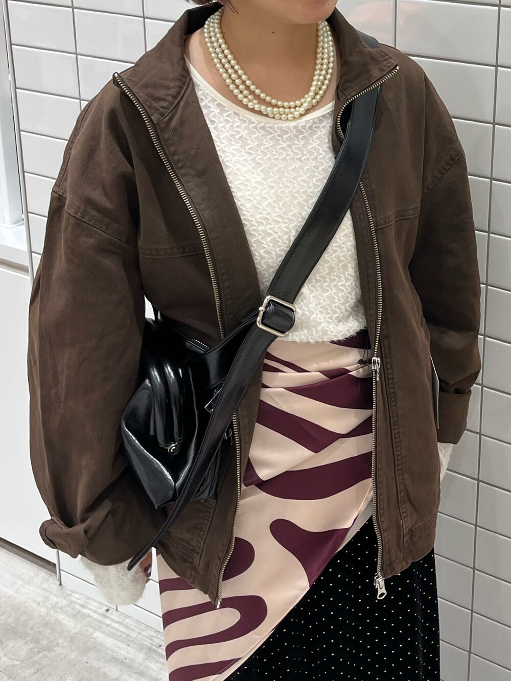 ブラウン系のデニムジャケット、ブラック系のショルダーバッグ、ホワイト系のTシャツ/カットソーを着用したレディースの秋コーディネートの4枚目の写真