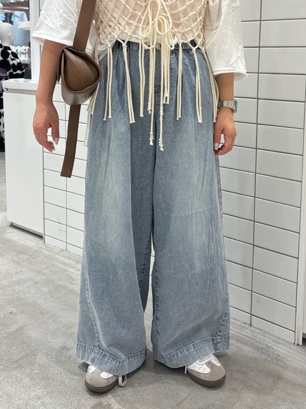 ブルー系のデニムパンツ、ホワイト系のベスト、ピンク系のタンクトップを着用したレディースの夏コーディネートの3枚目の写真