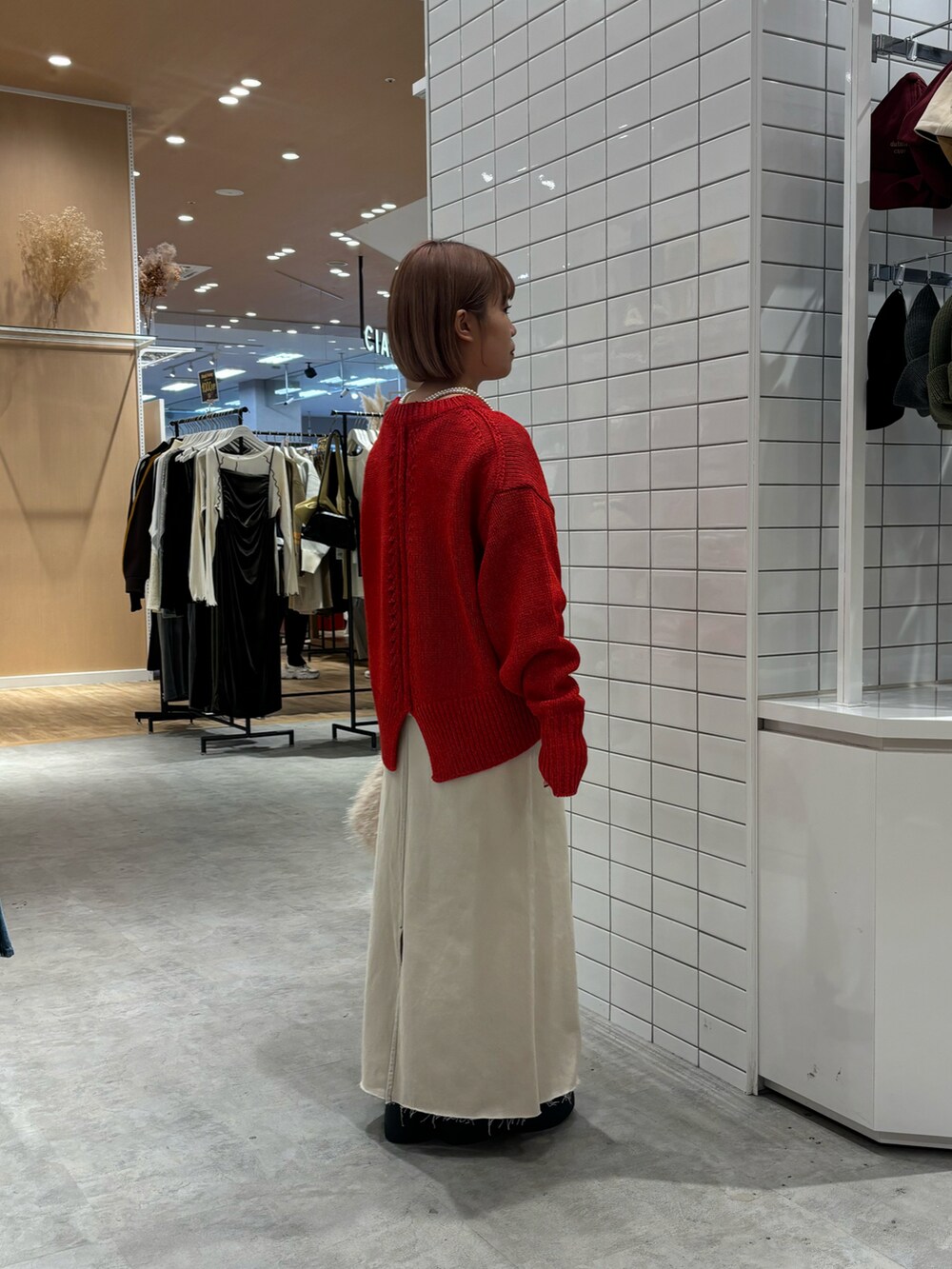 レッド系のニット/セーター、ホワイト系のTシャツ/カットソー、ホワイト系のデニムスカートを着用したレディースの秋コーディネートの4枚目の写真