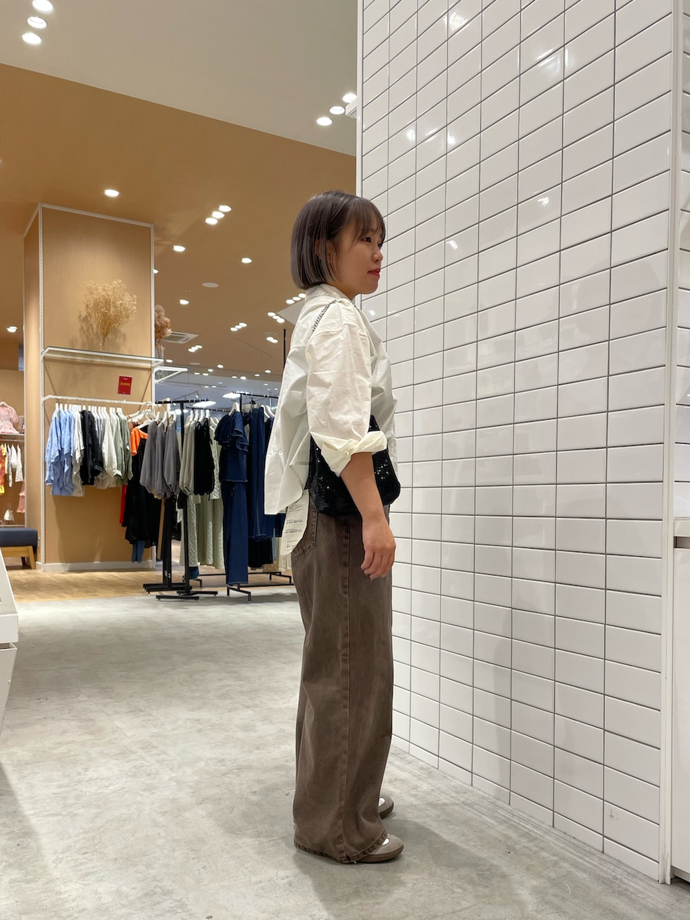 ホワイト系のシャツ/ブラウス、ブラック系のショルダーバッグ、ブラウン系のデニムパンツを着用したレディースの秋コーディネートの2枚目の写真