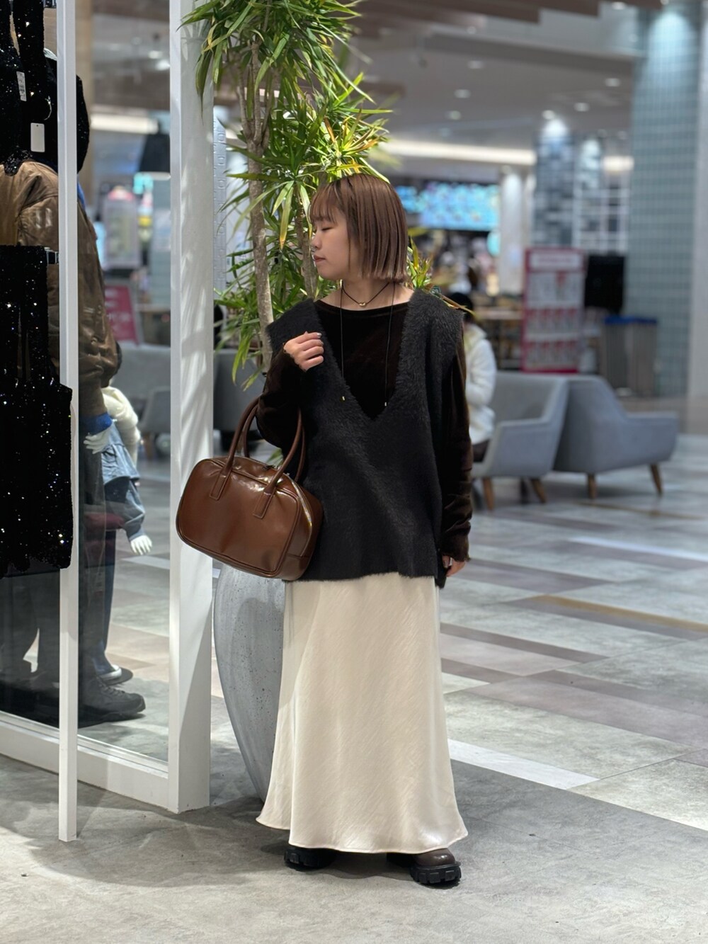 ブラウン系のボストンバッグ、ホワイト系のスカート、グレー系のベストを着用したレディースの冬コーディネートの2枚目の写真