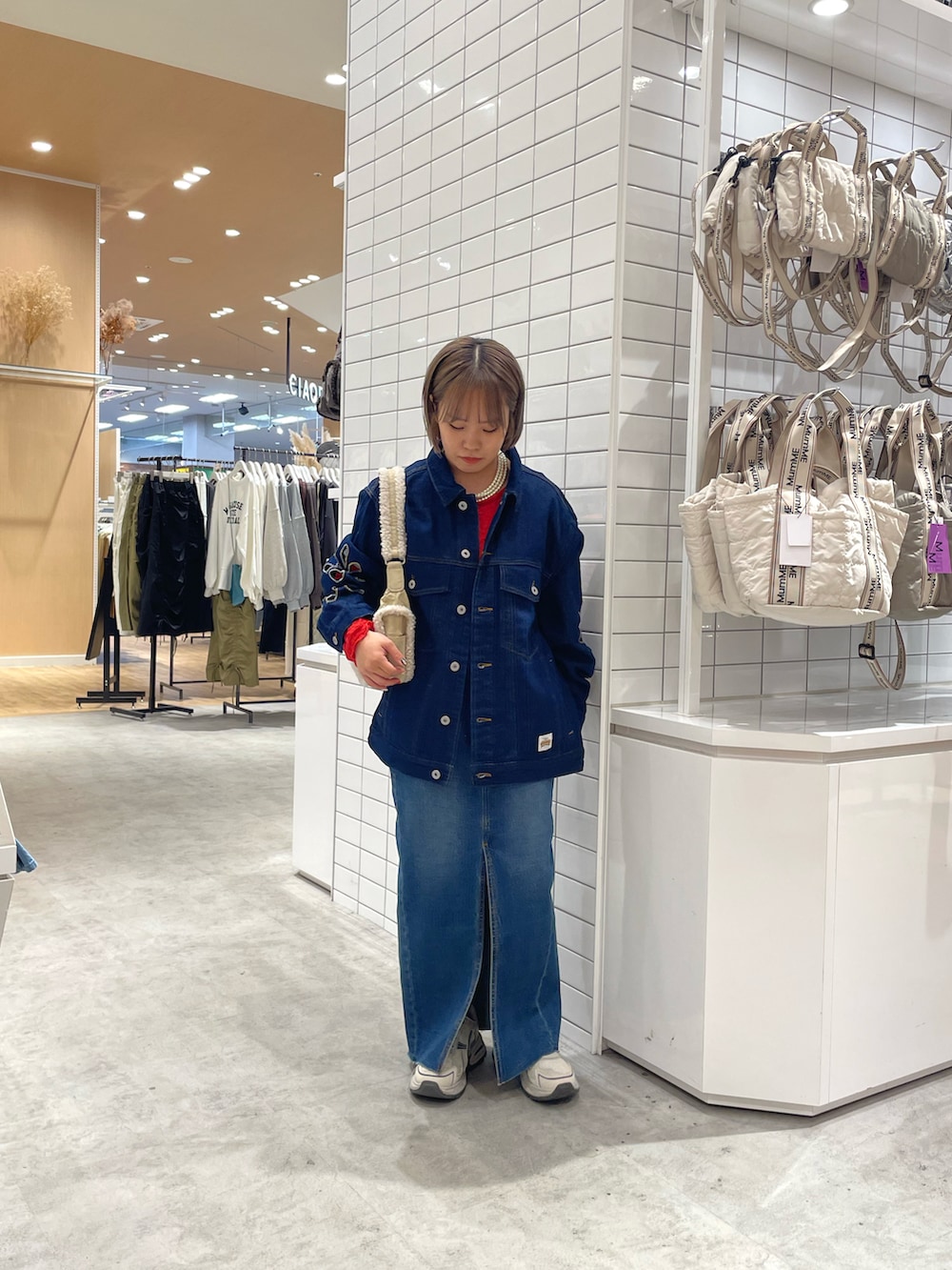 ブルー系のデニムジャケット、ブルー系のデニムスカート、ホワイト系のスニーカーを着用したレディースの秋コーディネートの2枚目の写真