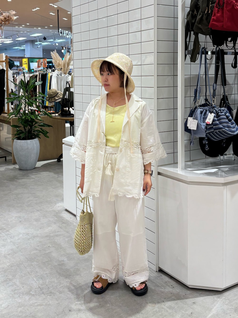 ホワイト系のその他パンツ、ブラウン系のサンダル、ゴールド系のトートバッグを着用したレディースの夏コーディネートの2枚目の写真