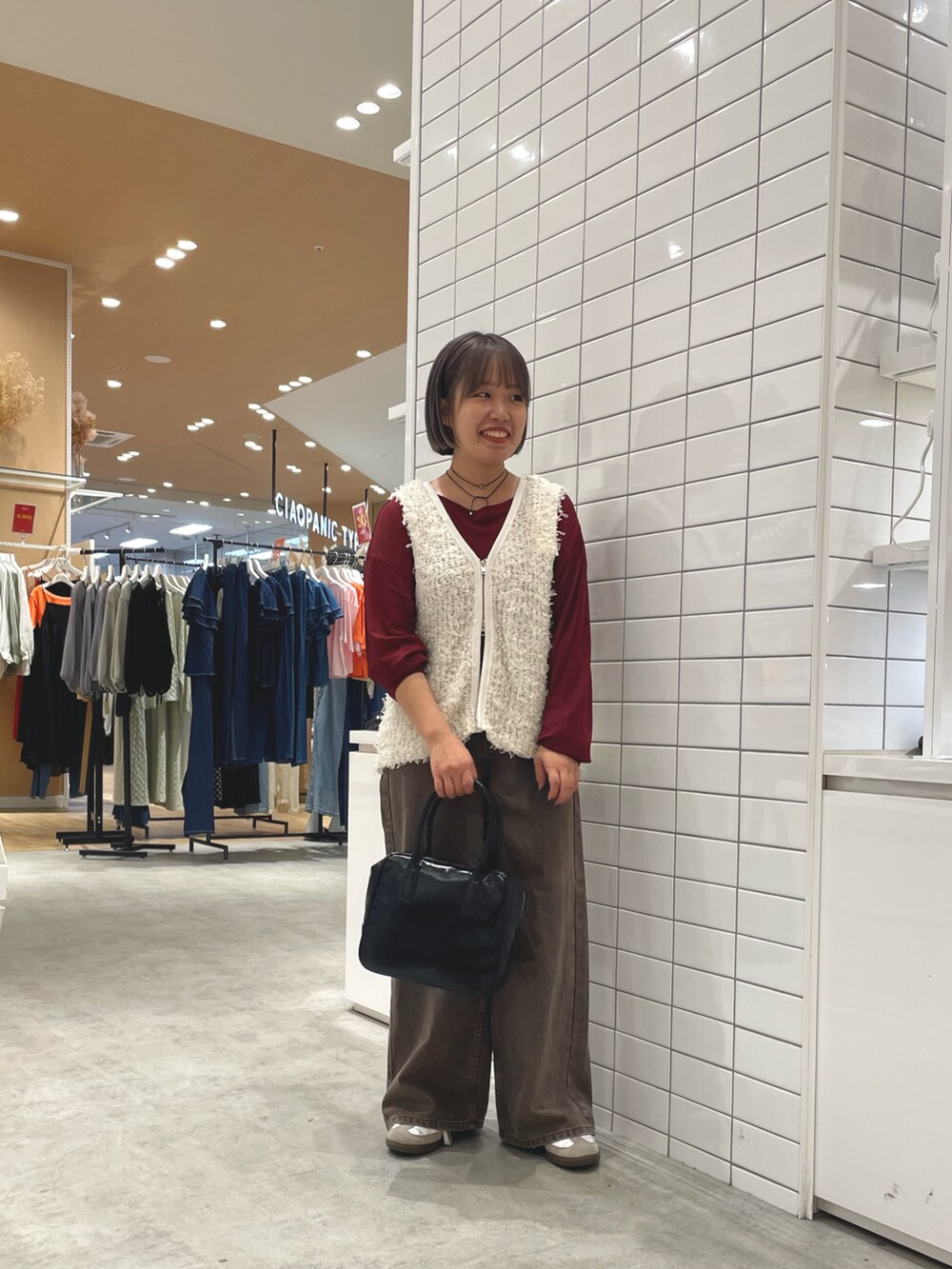 ホワイト系のベスト、レッド系のTシャツ/カットソー、ブラウン系のデニムパンツを着用したレディースの秋コーディネートの2枚目の写真