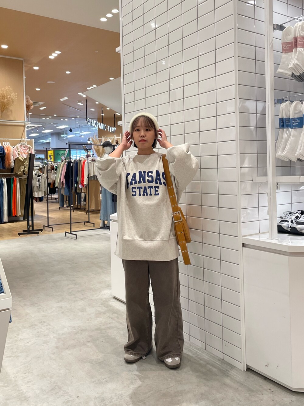 ブラウン系のデニムパンツ、ホワイト系のスウェット、ブラウン系のショルダーバッグを着用したレディースの秋コーディネートの2枚目の写真