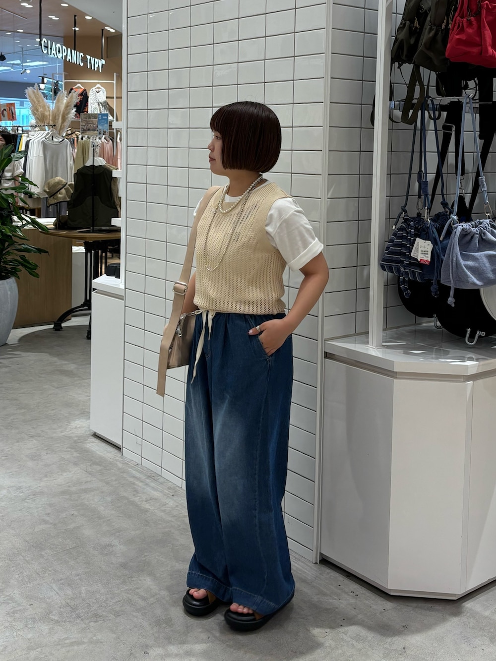 ブルー系のデニムパンツ、ブラウン系のサンダル、ホワイト系のTシャツ/カットソーを着用したレディースの夏コーディネートの2枚目の写真