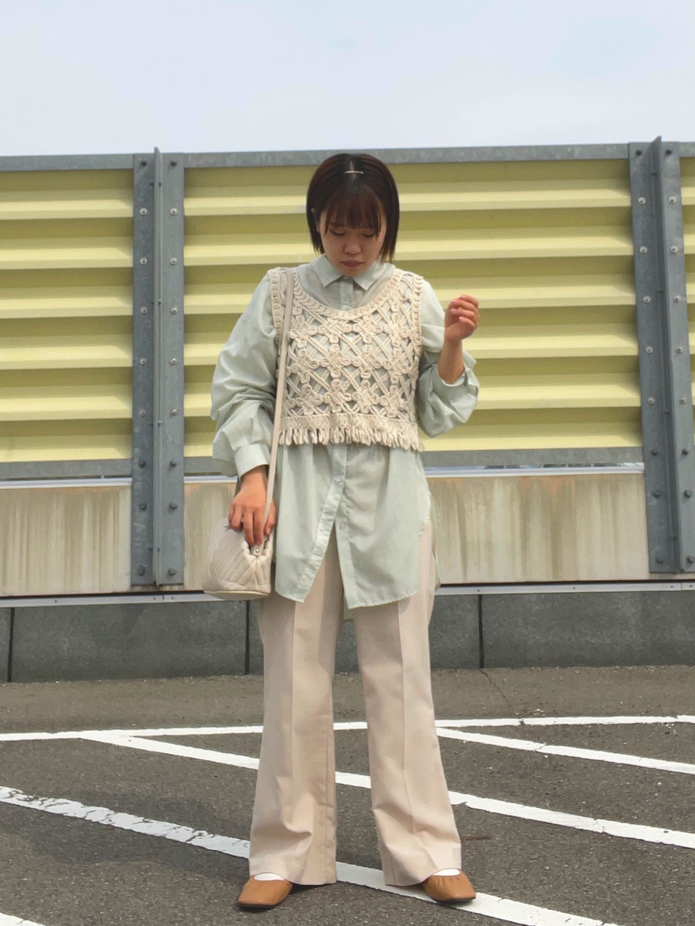 ベージュ系のスラックス、ベージュ系のベスト、ホワイト系のショルダーバッグを着用したレディースの春コーディネートの3枚目の写真