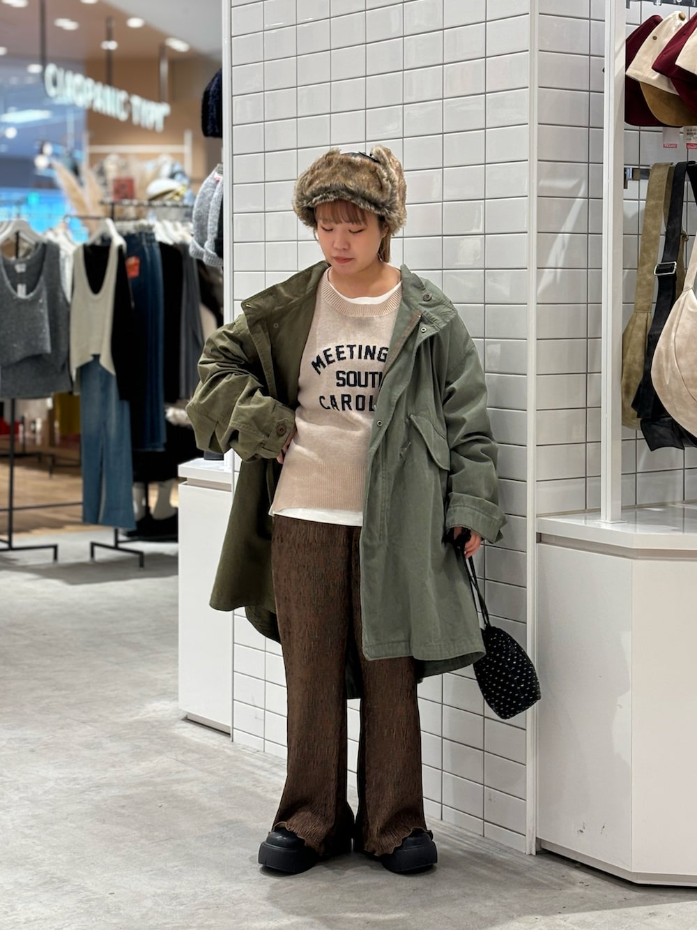 ブラック系のショルダーバッグ、ベージュ系のニット/セーター、グリーン系のモッズコートを着用したレディースの冬コーディネートの2枚目の写真