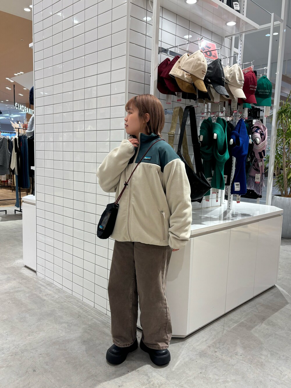 ホワイト系のブルゾン、ブラック系のショルダーバッグ、ブラウン系のデニムパンツを着用したレディースの春コーディネートの4枚目の写真