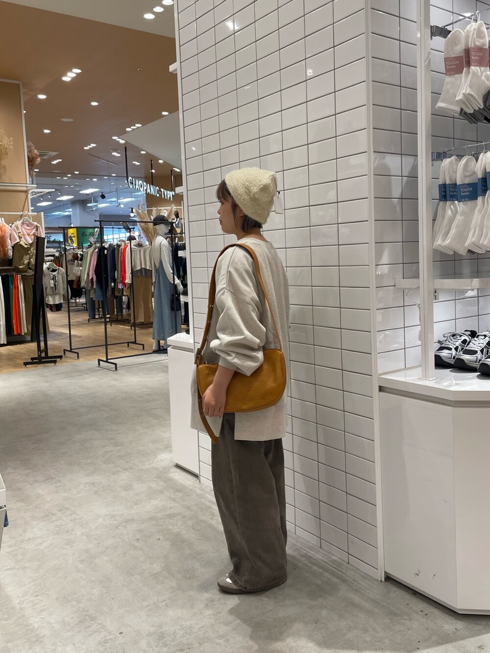 ブラウン系のデニムパンツ、ホワイト系のスウェット、ブラウン系のショルダーバッグを着用したレディースの秋コーディネートの4枚目の写真