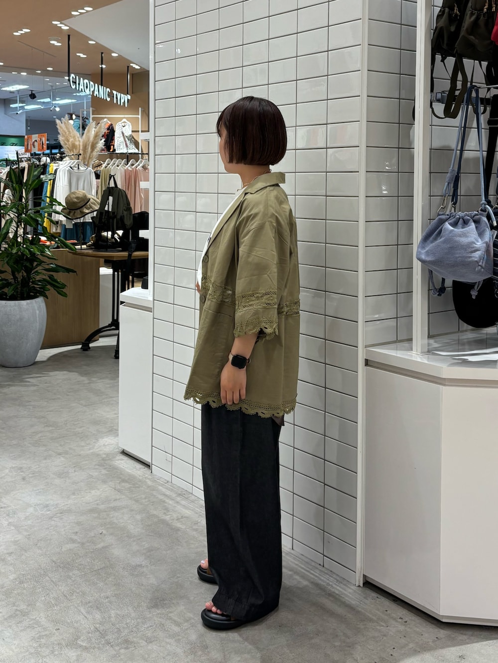 ブラック系のデニムパンツ、ブラウン系のサンダル、ホワイト系のTシャツ/カットソーを着用したレディースの夏コーディネートの2枚目の写真