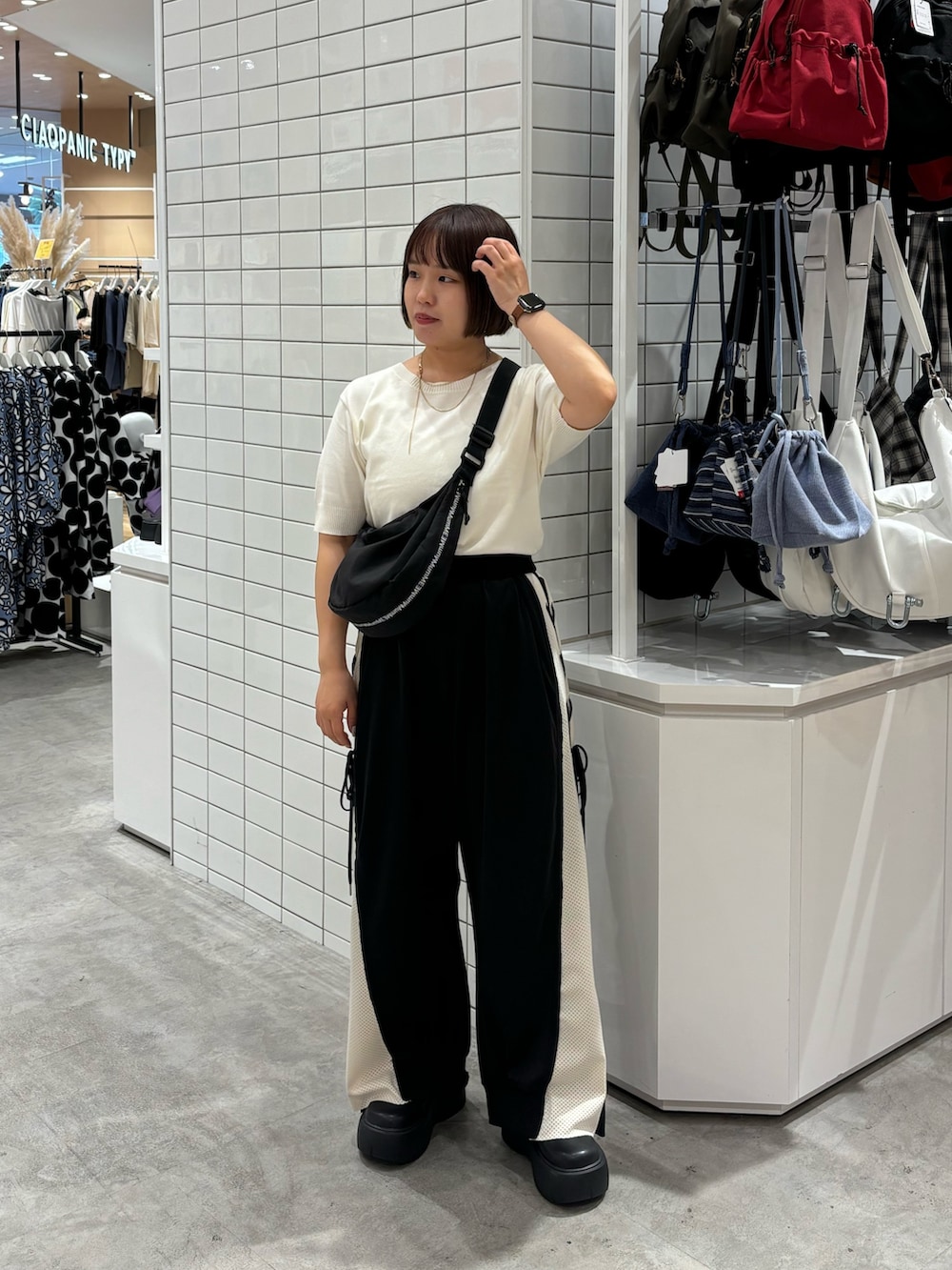 ブラック系のブーツ、ホワイト系のニット/セーター、ブラック系のショルダーバッグを着用したレディースの夏コーディネートの2枚目の写真