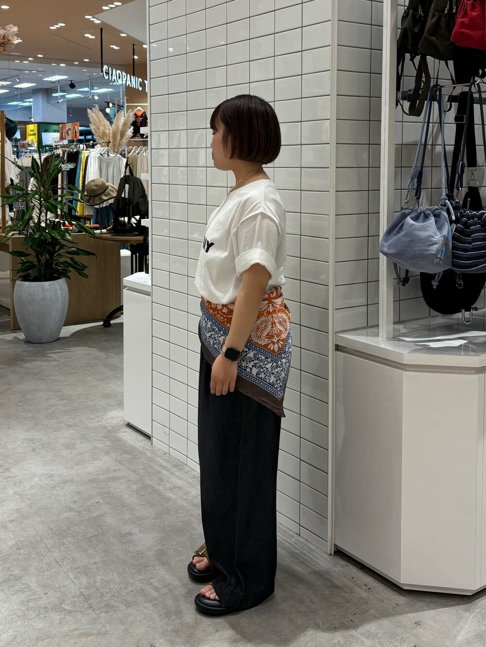 ブラック系のデニムパンツ、ブラウン系のサンダル、ホワイト系のTシャツ/カットソーを着用したレディースの夏コーディネートの2枚目の写真