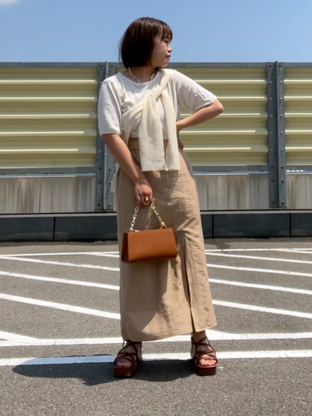 ブラウン系のサンダル、ベージュ系のスカート、ブラウン系のショルダーバッグを着用したレディースの夏コーディネートの2枚目の写真