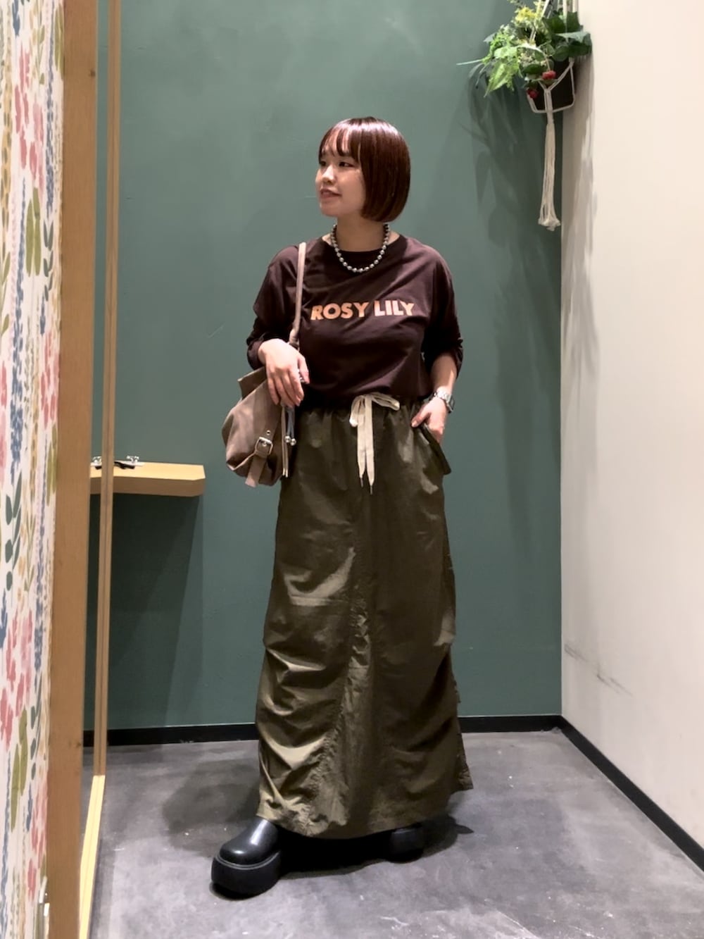 グリーン系のスカート、ブラック系のブーツ、ブラウン系のTシャツ/カットソーを着用したレディースの秋コーディネートの2枚目の写真