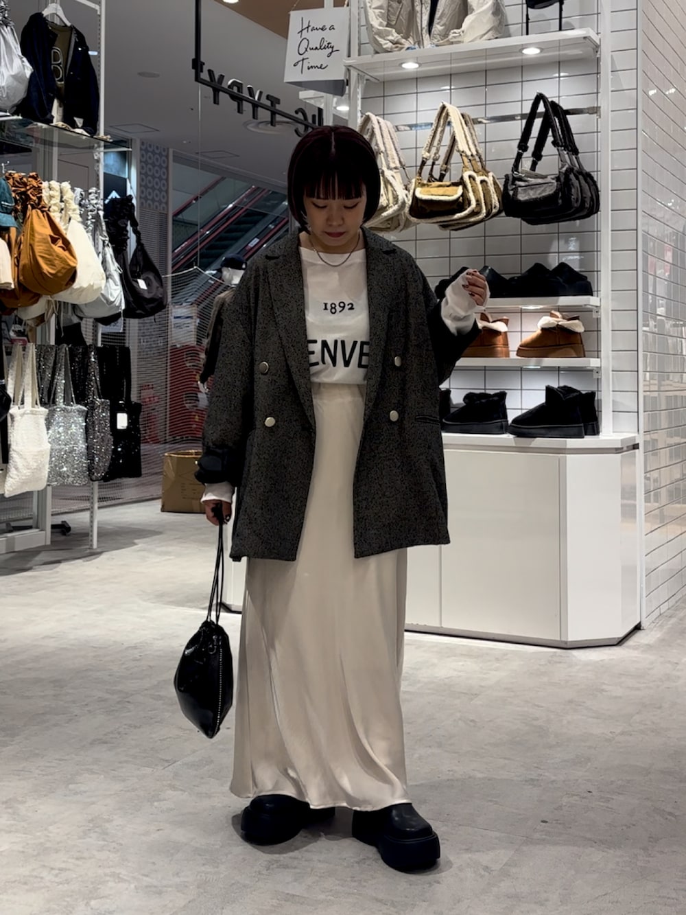 ホワイト系のスカート、ブラック系のブーツ、ホワイト系のTシャツ/カットソーを着用したレディースの秋コーディネートの2枚目の写真