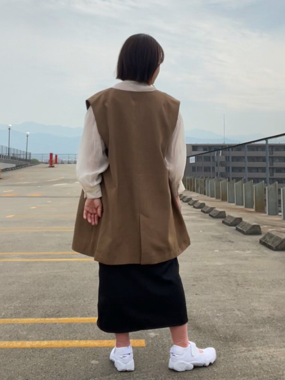 ホワイト系のシャツ/ブラウス、ブラウン系のベスト、ブラック系のスカートを着用したレディースの春コーディネートの3枚目の写真