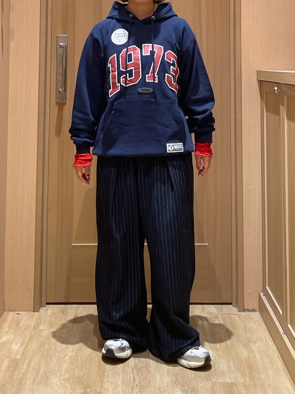 ブルー系のパーカー、ブルー系のスラックス、オレンジ系のTシャツ/カットソーを着用したレディースの秋コーディネートの2枚目の写真