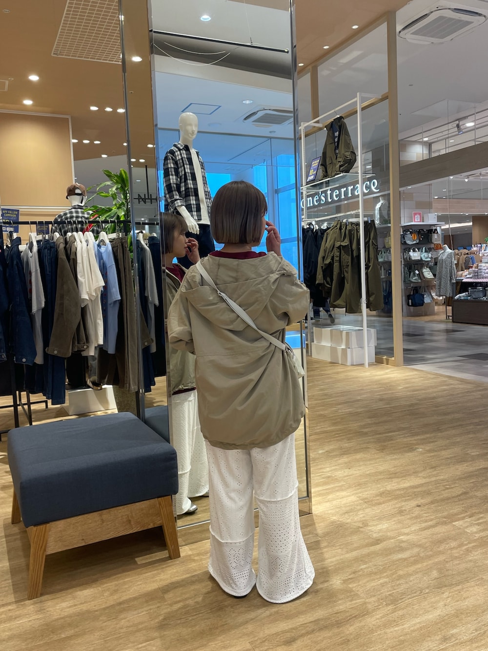 グレー系のマウンテンパーカー、レッド系のTシャツ/カットソー、ホワイト系のショルダーバッグを着用したレディースの秋コーディネートの2枚目の写真