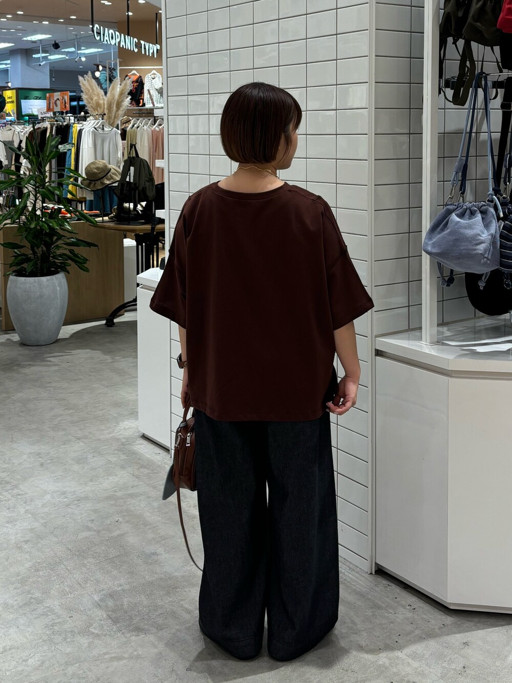 ブラック系のデニムパンツ、ブラウン系のトートバッグ、ブラウン系のサンダルを着用したレディースの夏コーディネートの2枚目の写真