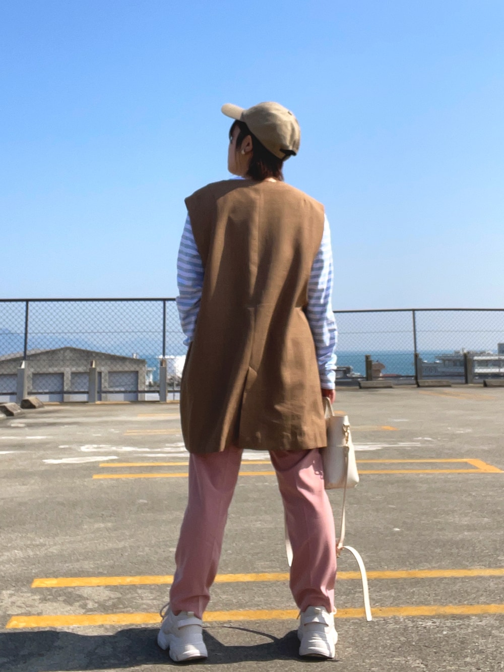 ブルー系のTシャツ/カットソー、ブラウン系のベスト、ホワイト系のショルダーバッグを着用したレディースの春コーディネートの3枚目の写真