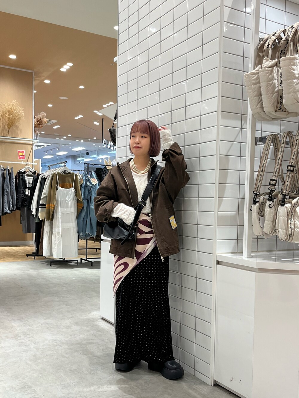 ブラウン系のデニムジャケット、ブラック系のショルダーバッグ、ホワイト系のTシャツ/カットソーを着用したレディースの秋コーディネートの2枚目の写真