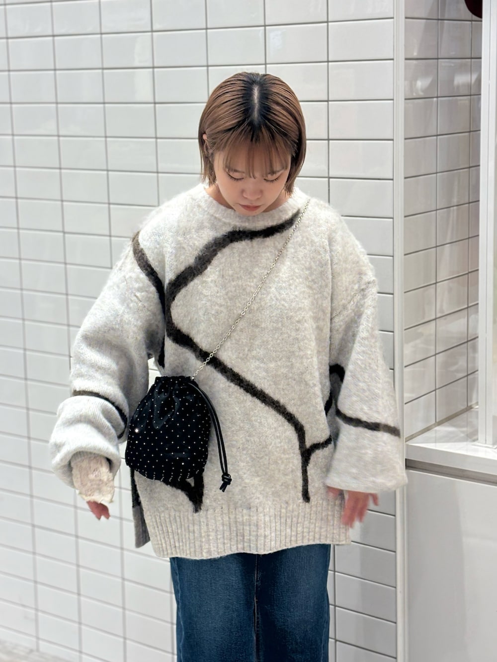 ホワイト系のニット/セーター、ブルー系のデニムスカート、ブラック系のブーツを着用したレディースの冬コーディネートの3枚目の写真