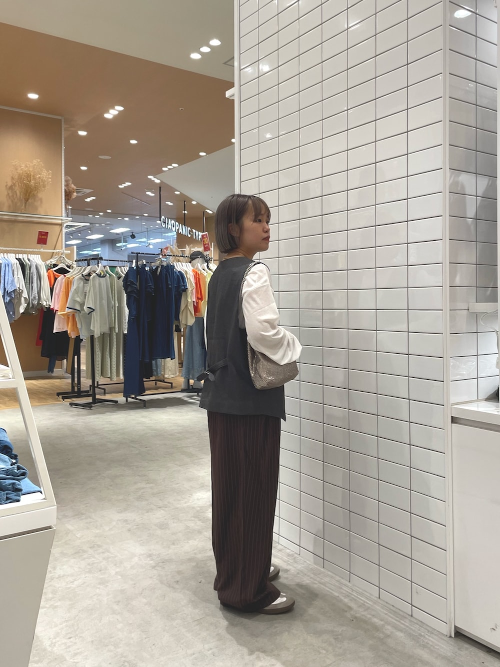 ホワイト系のTシャツ/カットソー、グレー系のベスト、ブラウン系のスラックスを着用したレディースの秋コーディネートの3枚目の写真