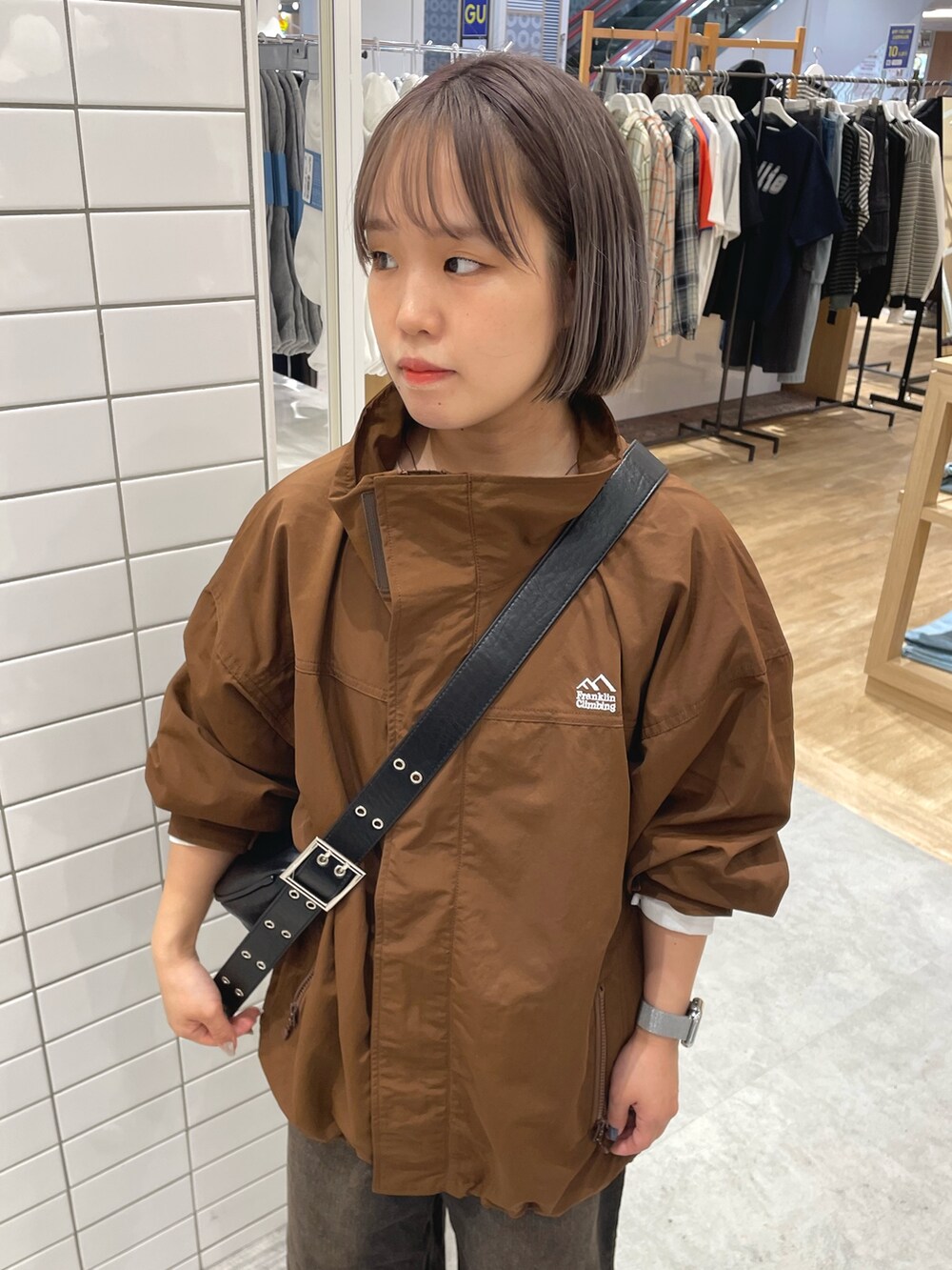 ブラウン系のナイロンジャケット、ブラック系のショルダーバッグ、ブラウン系のデニムパンツを着用したレディースの秋コーディネートの4枚目の写真