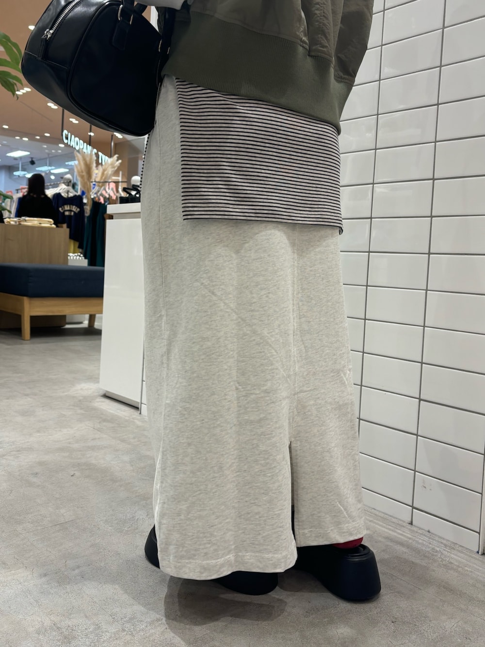 グリーン系のベスト、ブラック系のショルダーバッグ、ブラック系のサンダルを着用したレディースの春コーディネートの6枚目の写真