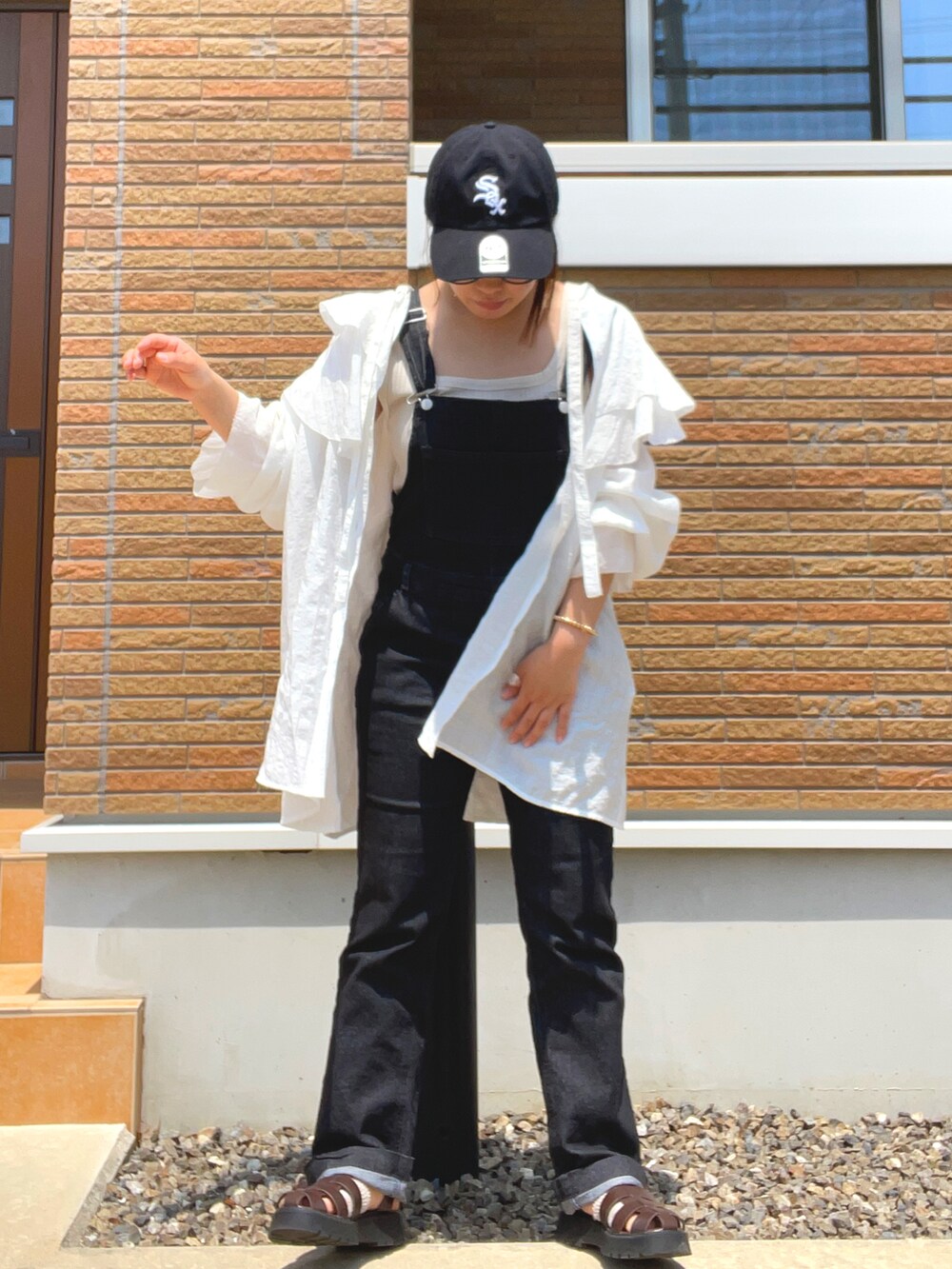 ブラック系のサロペット/オーバーオール、ホワイト系のシャツ/ブラウス、ブラウン系のサンダルを着用したレディースの春コーディネートの2枚目の写真