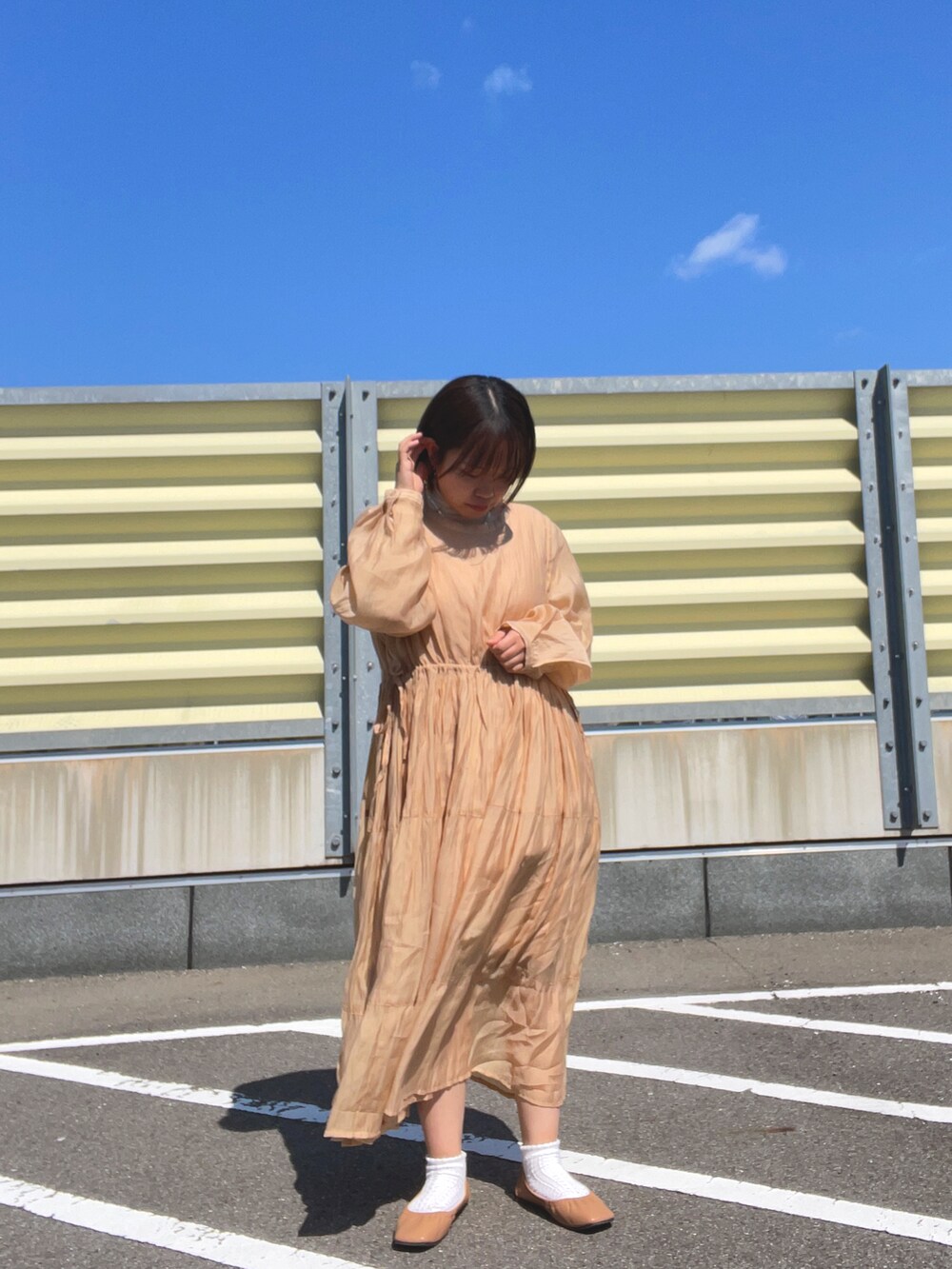 オレンジ系のワンピース、ブラウン系のベスト、ブラウン系のパンプスを着用したレディースの春コーディネートの5枚目の写真