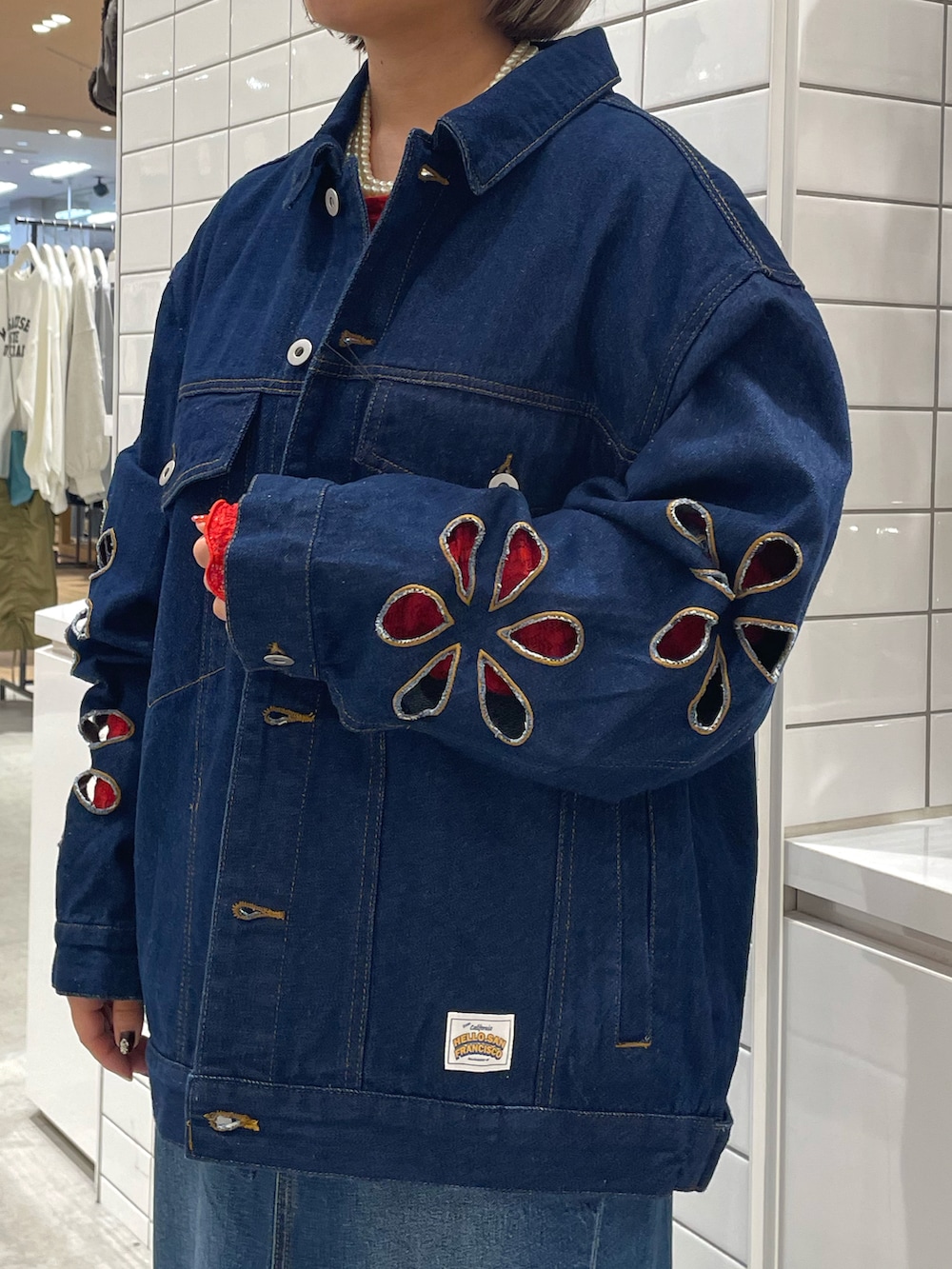 ブルー系のデニムジャケット、ブルー系のデニムスカート、ホワイト系のスニーカーを着用したレディースの秋コーディネートの4枚目の写真