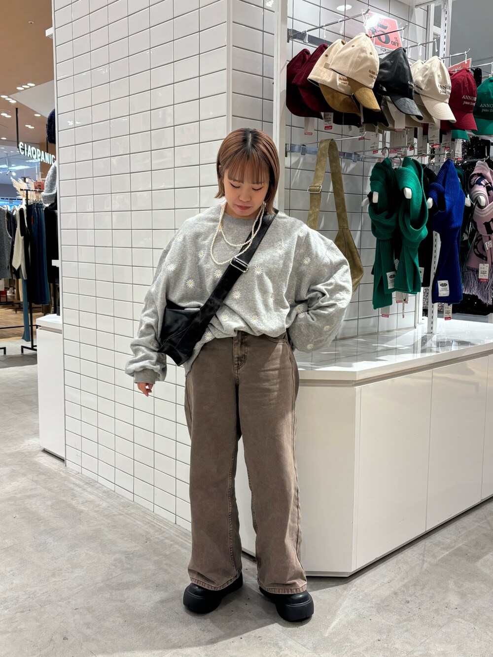 ブラック系のショルダーバッグ、ブラウン系のデニムパンツ、ブラック系のブーツを着用したレディースの冬コーディネートの2枚目の写真