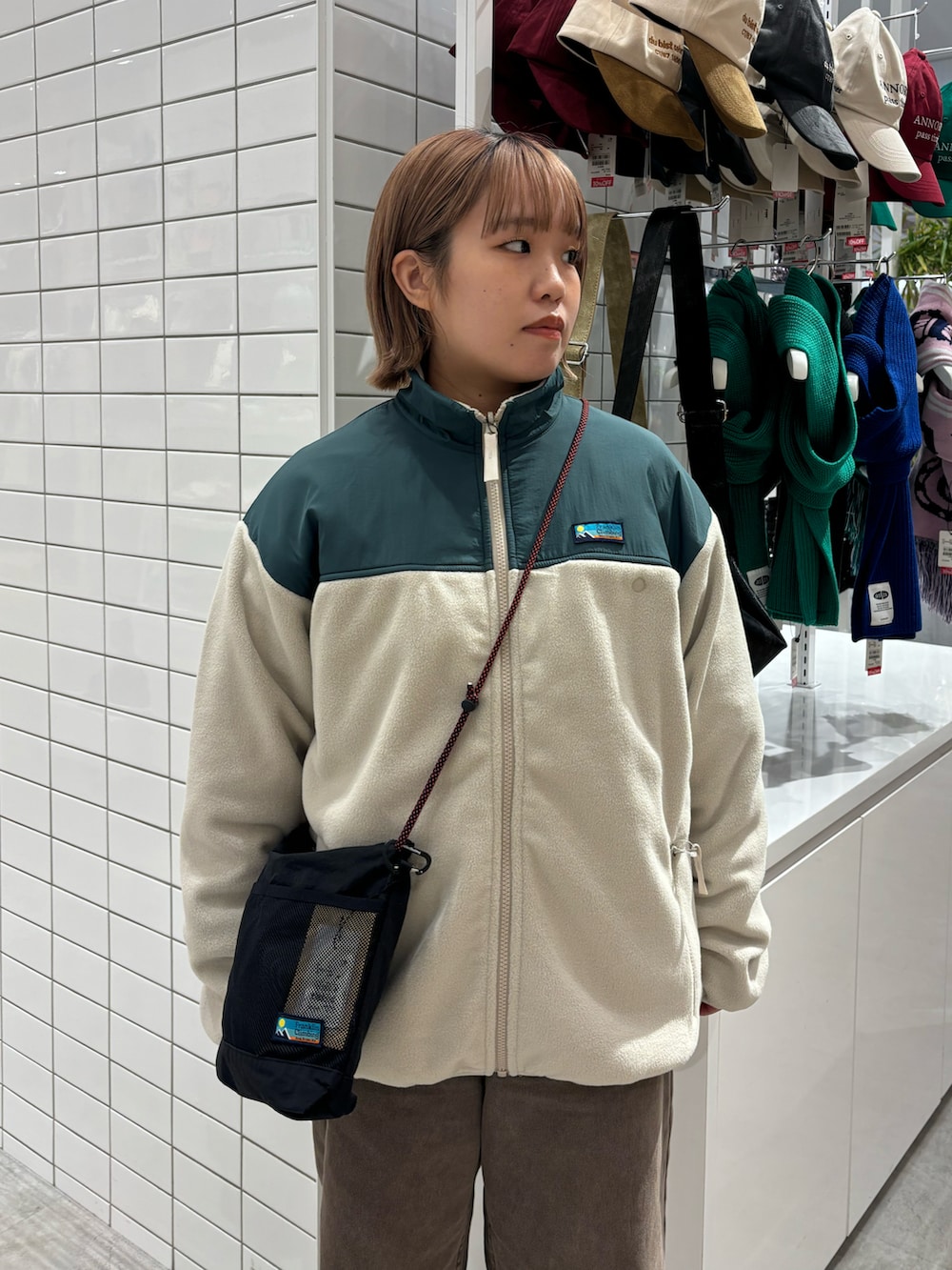 ホワイト系のブルゾン、ブラック系のショルダーバッグ、ブラウン系のデニムパンツを着用したレディースの春コーディネートの3枚目の写真