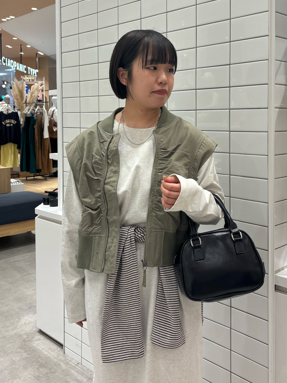 グリーン系のベスト、ブラック系のショルダーバッグ、ブラック系のサンダルを着用したレディースの春コーディネートの4枚目の写真