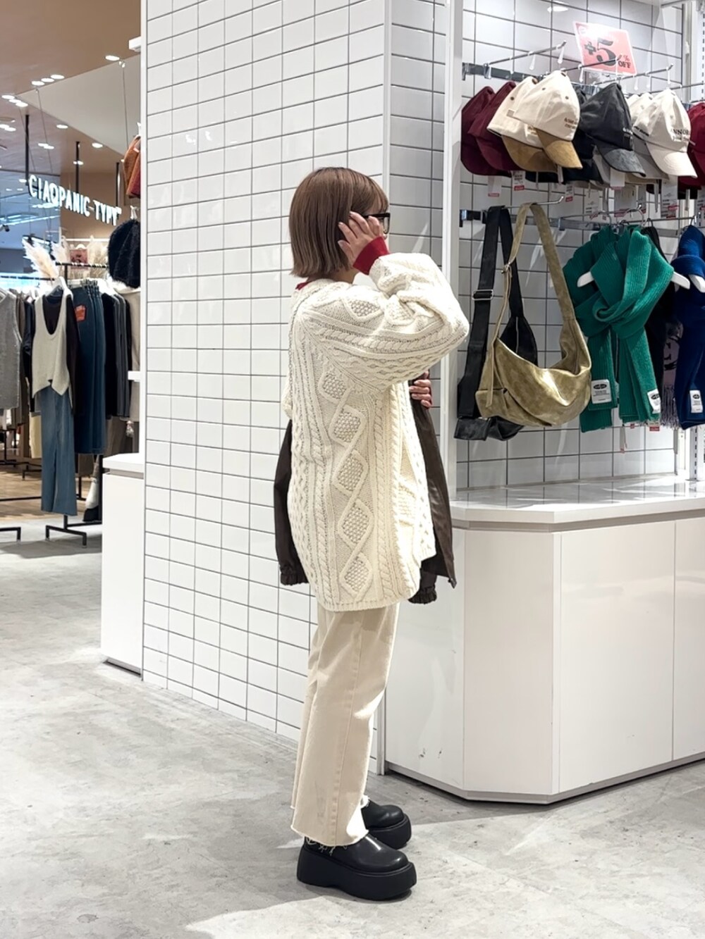 ブラウン系のライダースジャケット、ホワイト系のニット/セーター、ホワイト系のデニムパンツを着用したレディースの冬コーディネートの3枚目の写真