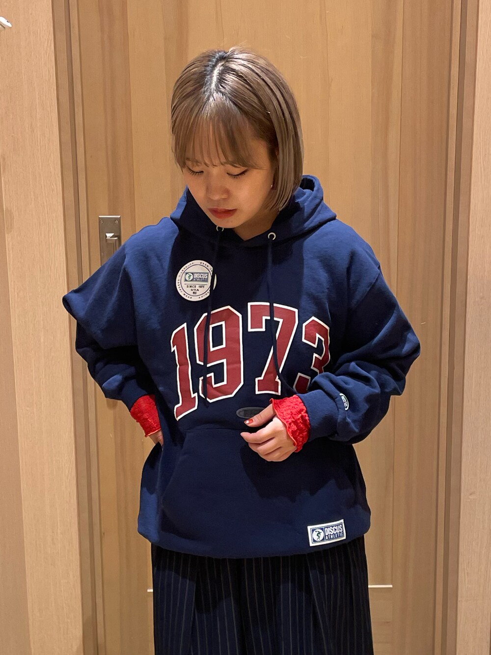 ブルー系のパーカー、ブルー系のスラックス、オレンジ系のTシャツ/カットソーを着用したレディースの秋コーディネートの4枚目の写真