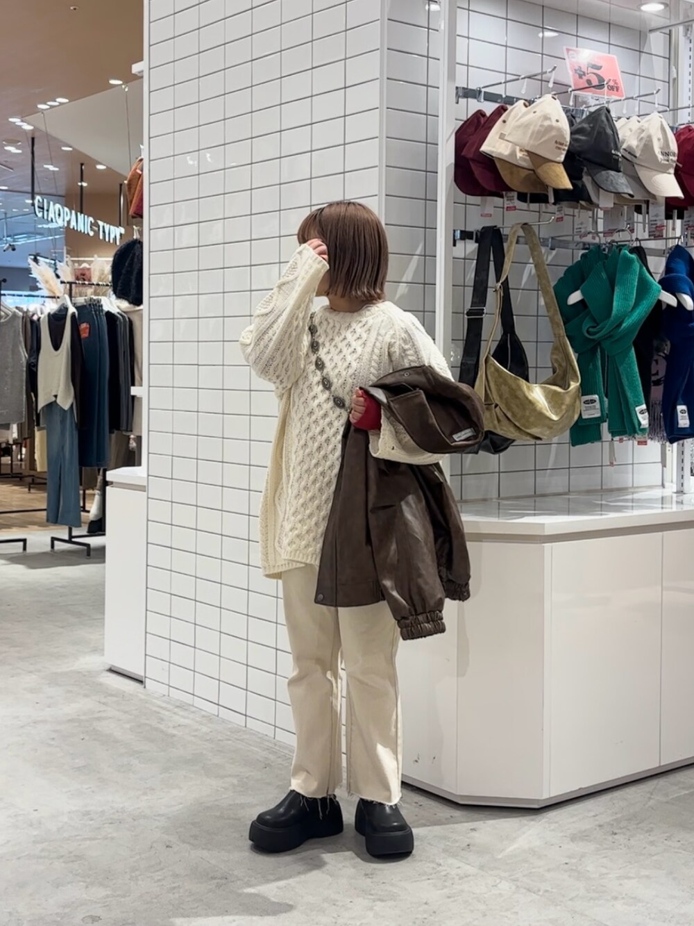 ブラウン系のライダースジャケット、ホワイト系のニット/セーター、ホワイト系のデニムパンツを着用したレディースの冬コーディネートの2枚目の写真