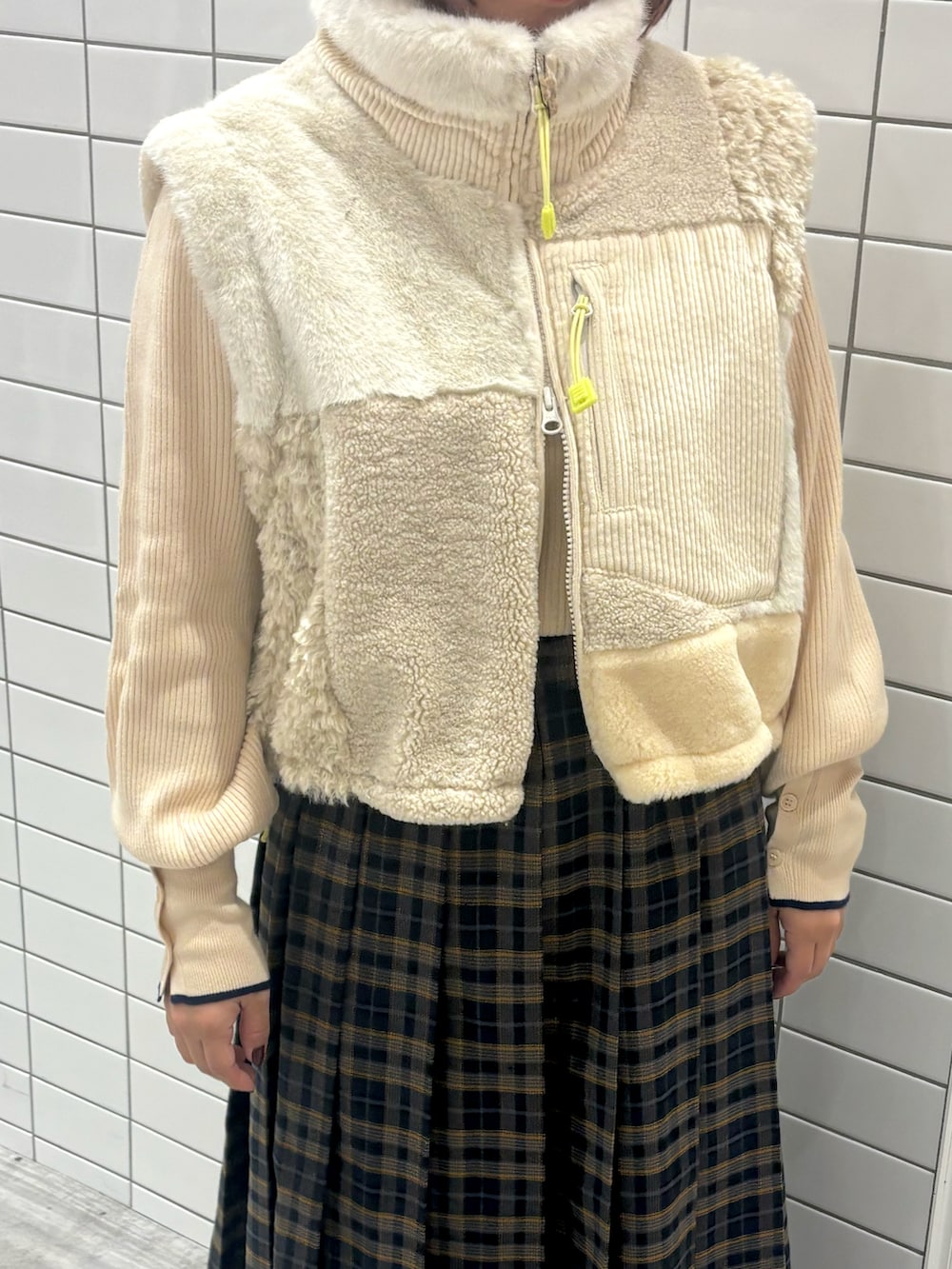 ブルー系のスカート、ブラウン系のブーツ、ホワイト系のベストを着用したレディースの秋コーディネートの3枚目の写真