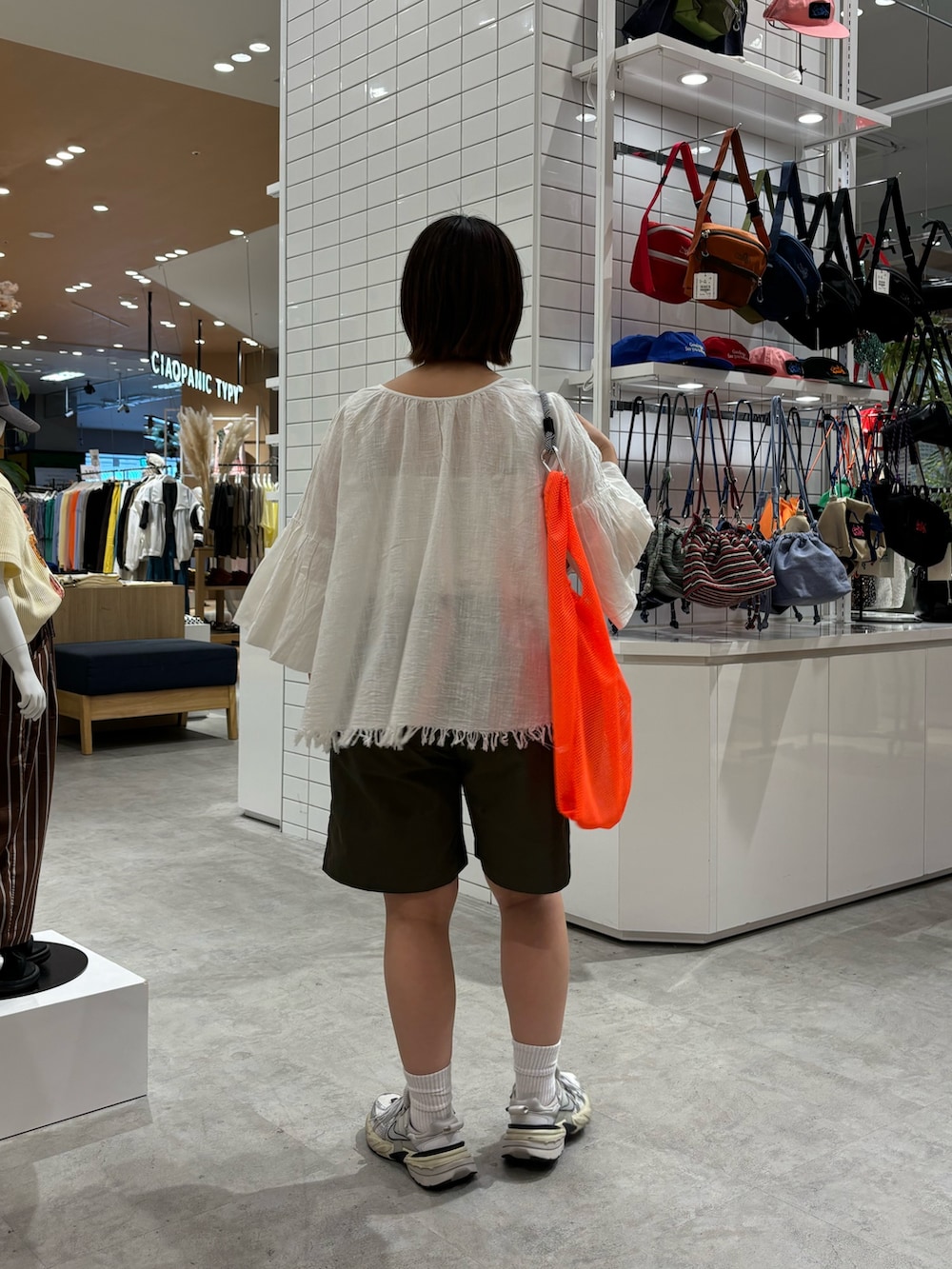 ホワイト系のシャツ/ブラウス、オレンジ系のトートバッグ、グリーン系のその他パンツを着用したレディースの春コーディネートの4枚目の写真