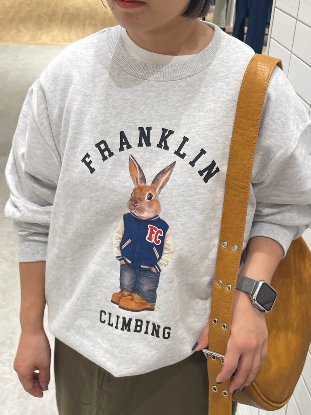 グレー系のスウェット、ブラウン系のショルダーバッグ、グリーン系のスカートを着用したレディースの秋コーディネートの3枚目の写真